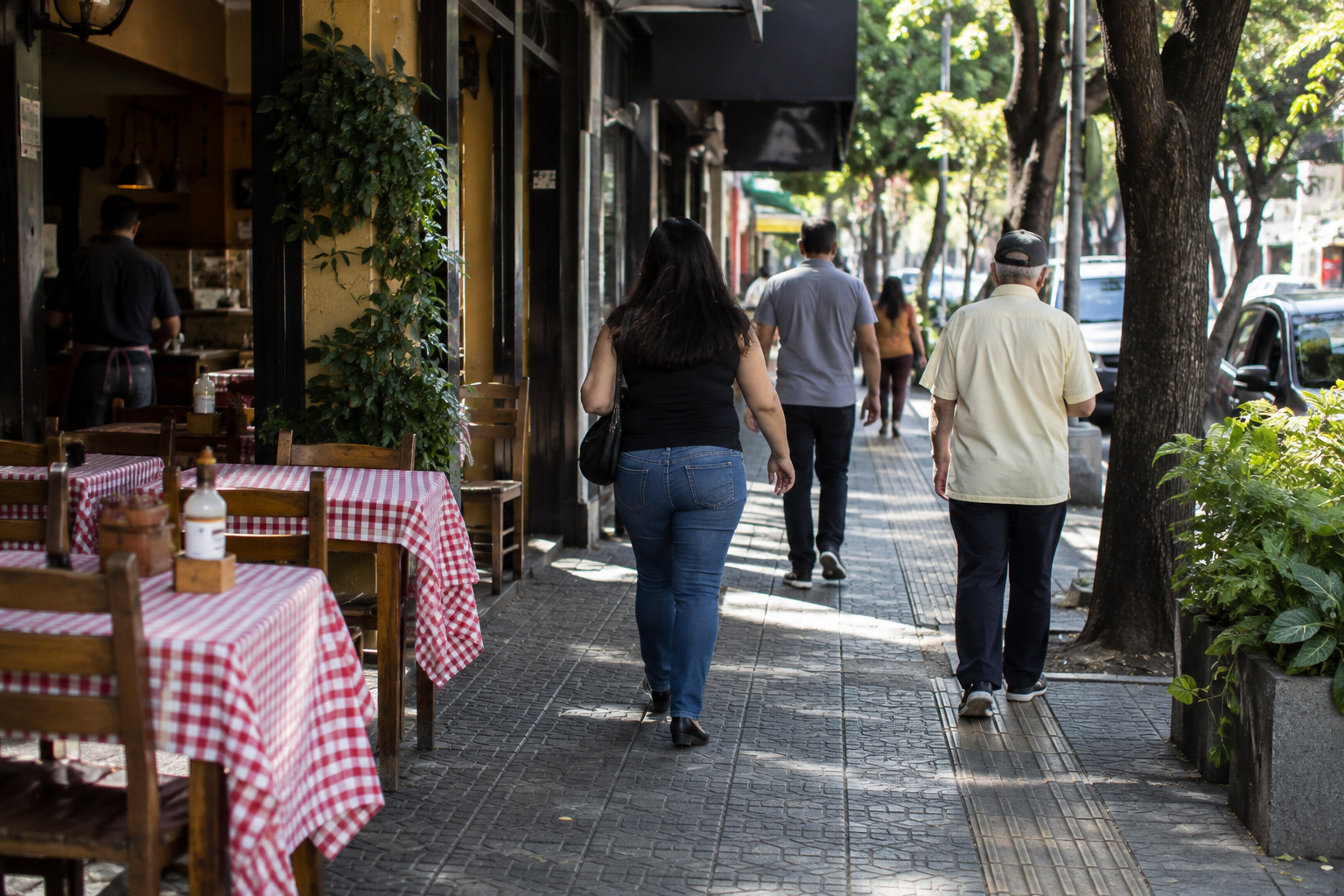 Calçada de rua comercial em cidade mineira, com mesas de restaurante e pedestres vistos de costas.