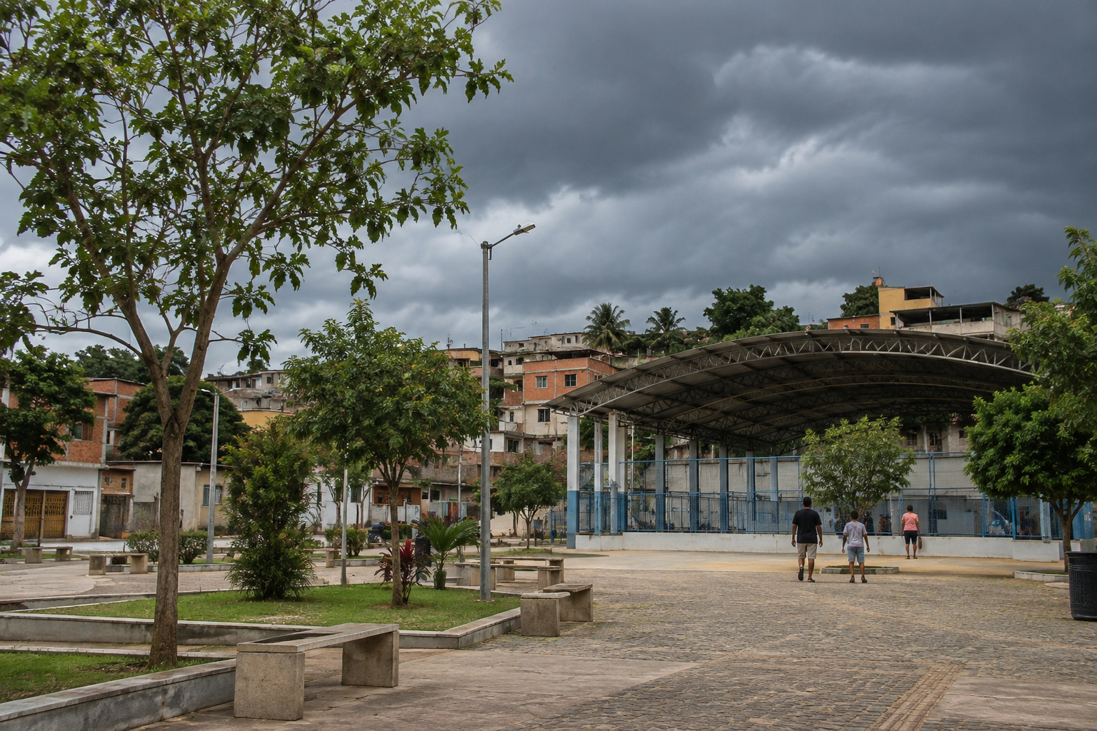 Praça urbana em Minas Gerais sob céu nublado, com árvores e pessoas próximas a um espaço coberto.